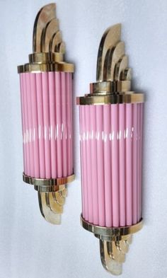 two pink and gold sconces mounted on a wall