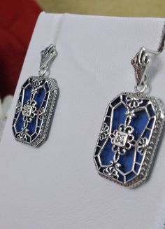 "Blue Camphor Glass Earrings Description MADE TO ORDER I now offer these lovely Art Deco reproduction earrings in sterling silver These earrings were recast from the exact design of an Antique ring. Each flawless blue sapphire glass is 3/4\" of an inch long and 9/16th of an inch wide. One 1.5mm White CZ gem graces the center of each earring. The earrings are 1 1/8 inches long, it is 3/4th\" (20mm) wide. Notice the beautiful design of the Deco filigree setting. (The matching ring is also availabl Blue Art Deco Wedding Earrings, Blue Filigree Art Deco Jewelry, Art Deco Blue Filigree Jewelry, Vintage Hallmarked Blue Jewelry, Vintage Blue Hallmarked Jewelry, Blue Art Deco Jewelry For Evening, Blue Elegant Earrings, Antique Blue Jewelry With Filigree, Antique Blue Filigree Jewelry