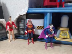 three action figures are standing in front of a toy set that includes superman, batman and the flash