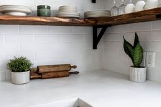 a kitchen counter topped with lots of white plates and bowls next to a wooden shelf