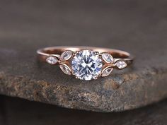 a rose gold engagement ring with three stone accents on top and an oval diamond in the middle