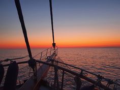 the sun is setting over the ocean on a boat