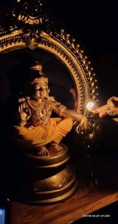 a gold statue sitting on top of a wooden table next to a light in the dark