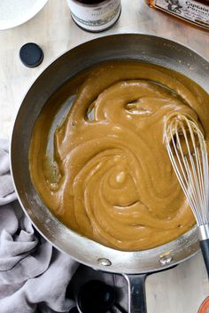 a metal pan filled with peanut butter and whisk