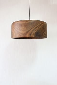 a wooden light fixture hanging from a ceiling in front of a white wall and floor