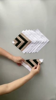 two hands are holding strips of paper on a table