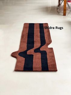 an orange and black rug on the floor in a room with several chairs behind it