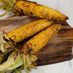 grilled corn on the cob sitting on a cutting board