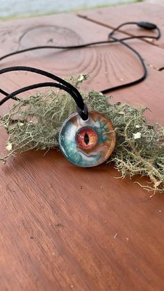 This handcrafted dragon eye necklace is a unique piece that is sure to be a statement pieces. I created this epoxy resin necklace with a glass faux eye that I have encased in eco epoxy resin. The background is swirled copper, hunter green, and white colored epoxy resin. This pendant will make a special gift for him. -Pendant Sizing- 1 inch diameter  -This pendant includes a pull apart clasp corded necklace-  -Necklace can be sized from 16-24 inches- -All necklaces include a small necklace box or Mystical Resin Necklaces For Gifts, Handmade Mystical Resin Jewelry, Adjustable Resin Round Pendant Necklace, Unique Eye-shaped Jewelry For Gifts, Hand Painted Spiritual Resin Jewelry, North Carolina Nature, Dragon Eye Necklace, Epoxy Resin Necklace, Colored Epoxy Resin