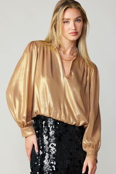 This split-neck blouse has a decadent feel thanks to its lustrous metallic sheen. It has gentle gathers and puffed long sleeves finished by button cuffs. •Split neckline •Long sleeves •Button cuffs •Bubble hem Item number 2330079 100% Polyester Chic Sheen Tops For Fall, Chic Fall Tops With Sheen, Fall Evening Blouse With Gathered Sleeves, Evening Blouse With Gathered Sleeves For Fall, Chic Sheen Blouse For Night Out, Chic Long Sleeve Tops With Sheen, Chic Blouse With Sheen For Night Out, Chic Long Sleeve Puff Sleeve Top For Party, Metallic Long Sleeve Tops For Work