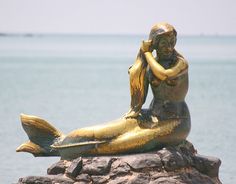 a statue of a mermaid sitting on top of a rock