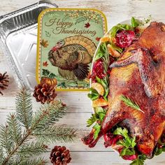 a roasted turkey on a platter with holiday decorations and pine cones next to it