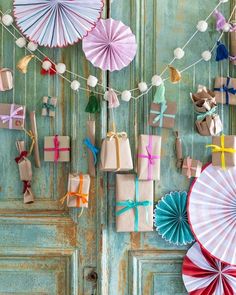 paper umbrellas and gift bags are hanging on the wall next to an old door