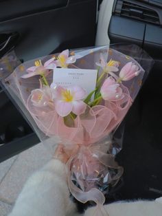 a bouquet of pink flowers wrapped in cellophane and sitting on the back seat of a car