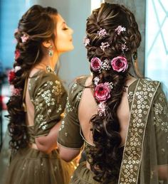 a woman with long hair and flowers in her hair is looking at herself in the mirror