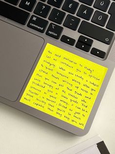 a laptop computer sitting on top of a desk with a yellow sticky note attached to the keyboard