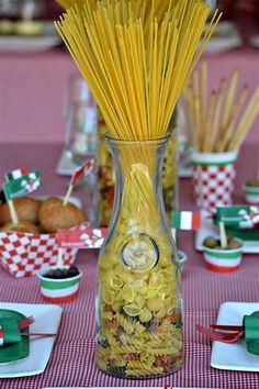 a vase filled with pasta sitting on top of a table next to other plates and cups