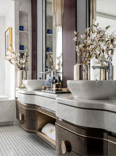 a bathroom with two sinks, mirrors and gold trim around the edges is shown in this image