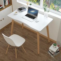 a laptop computer sitting on top of a white desk next to a book shelf and window