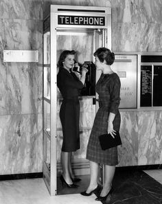 two women standing in front of a telephone booth