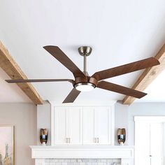 a ceiling fan mounted on the side of a fireplace in a room with white cabinets