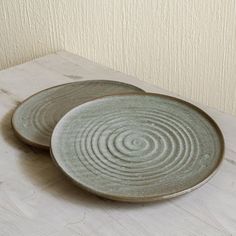 two plates sitting on top of a wooden table next to each other, one with spiral designs