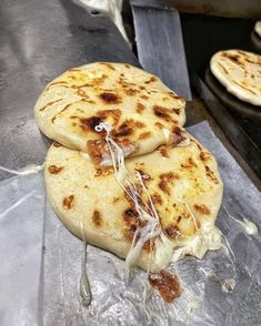 three pita breads sitting on top of a piece of tin foil covered in melted cheese