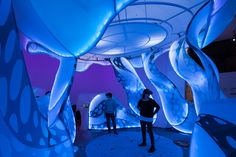 two people are standing in front of an art installation that looks like flowing blue water