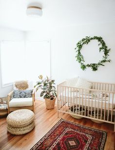 a baby's room with a crib, rocking chair, rug and potted plant