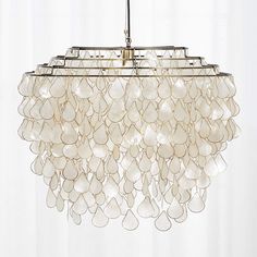 a chandelier made out of white glass beads hanging from a ceiling fixture in a living room