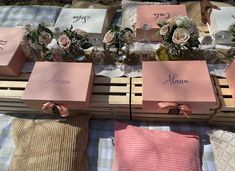 pink boxes with names and flowers on them are sitting on a plaid cloth covered tablecloth