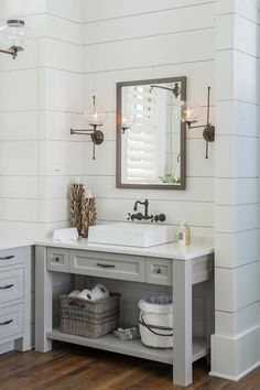 a bathroom with white walls and wood flooring is pictured in this image, there are two sinks under the mirror