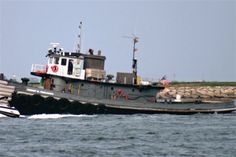 a tug boat is in the water near some rocks