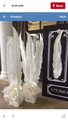 two vases with white flowers and feathers on them next to a sign that says atelle - co