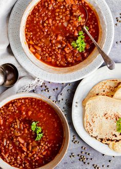 two bowls filled with beans and tortillas on top of a table