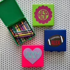 three small boxes with personalized crayons and pencils in them on a table