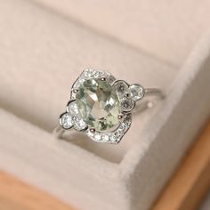 an engagement ring in a box with diamonds on the bottom and green amethyst