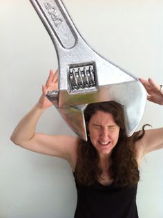 a woman holding up a large metal object over her head with two keys attached to it