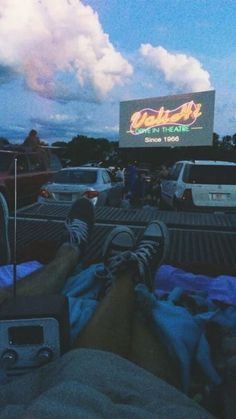 people are sitting in the back of a truck with their feet up and watching a movie