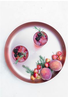 two glasses filled with fruit sitting on top of a plate