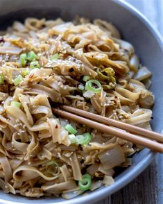 a bowl filled with noodles and vegetables next to chopsticks