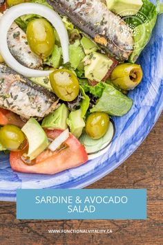 a salad with fish, tomatoes, avocado and olives in it on a blue plate