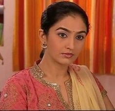 a woman in a pink and yellow sari is looking at the camera with an intense look on her face