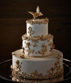 a three tiered white wedding cake with gold decorations