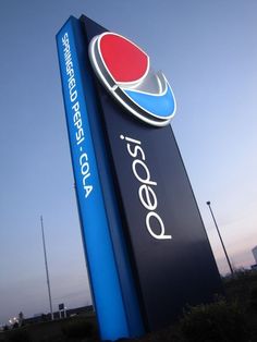 a pepsi sign is shown in front of an empty field and blue sky with the words pepsi on it