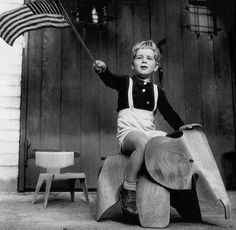 a young boy riding on the back of an elephant with an american flag in it's trunk