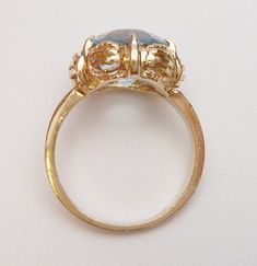 This is a classic birthstone ring from the 1960s. This ring has an oval step cut synthetic blue stone in the center that measures 12 x 10 mm. The cut is very different than a normal oval cut stone, so it has a neat look to it. The stone is set in 6 prongs and the ring has a cut out scalloped design around the stone. The inside of the ring is stamped JUB 100 10 (the K has worn off) and the ring has been tested to verify that it is 10 karat yellow gold. The ring weighs 3.9 grams and is a size 5.75 Vintage Oval Cabochon Sapphire Ring For Formal Occasions, Vintage Oval Cabochon Sapphire Ring Hallmarked, Vintage Sapphire Oval Cabochon Ring Hallmarked, Vintage Oval Cabochon Sapphire Ring With Hallmark, Vintage Oval Cabochon Sapphire Ring, Vintage Oval Sapphire Ring Hallmarked, Vintage Oval Sapphire Ring With Hallmark, Formal Oval Blue Topaz Birthstone Ring, Vintage Yellow Gold Rings With Blue Topaz