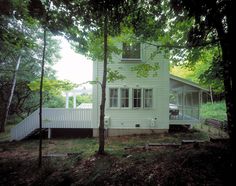 a white house in the woods with trees around it