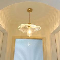 a light that is hanging from the ceiling above a window in a room with white walls