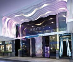 the entrance to an upscale shopping mall at night with lights shining on the building's facade